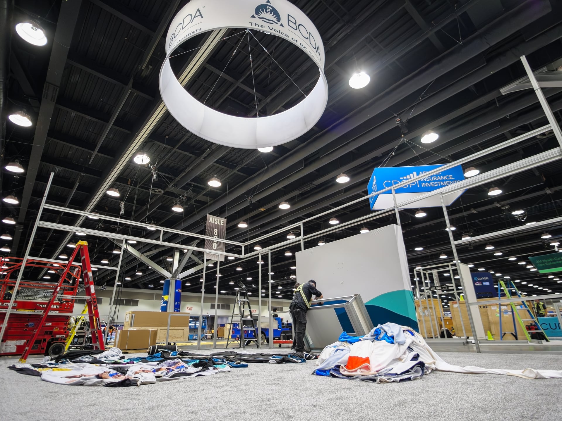 Early move-in at the Vancouver Convention Centre, with a BCDA-branded balloon overhead and crew unpacking booth materials on the floor.